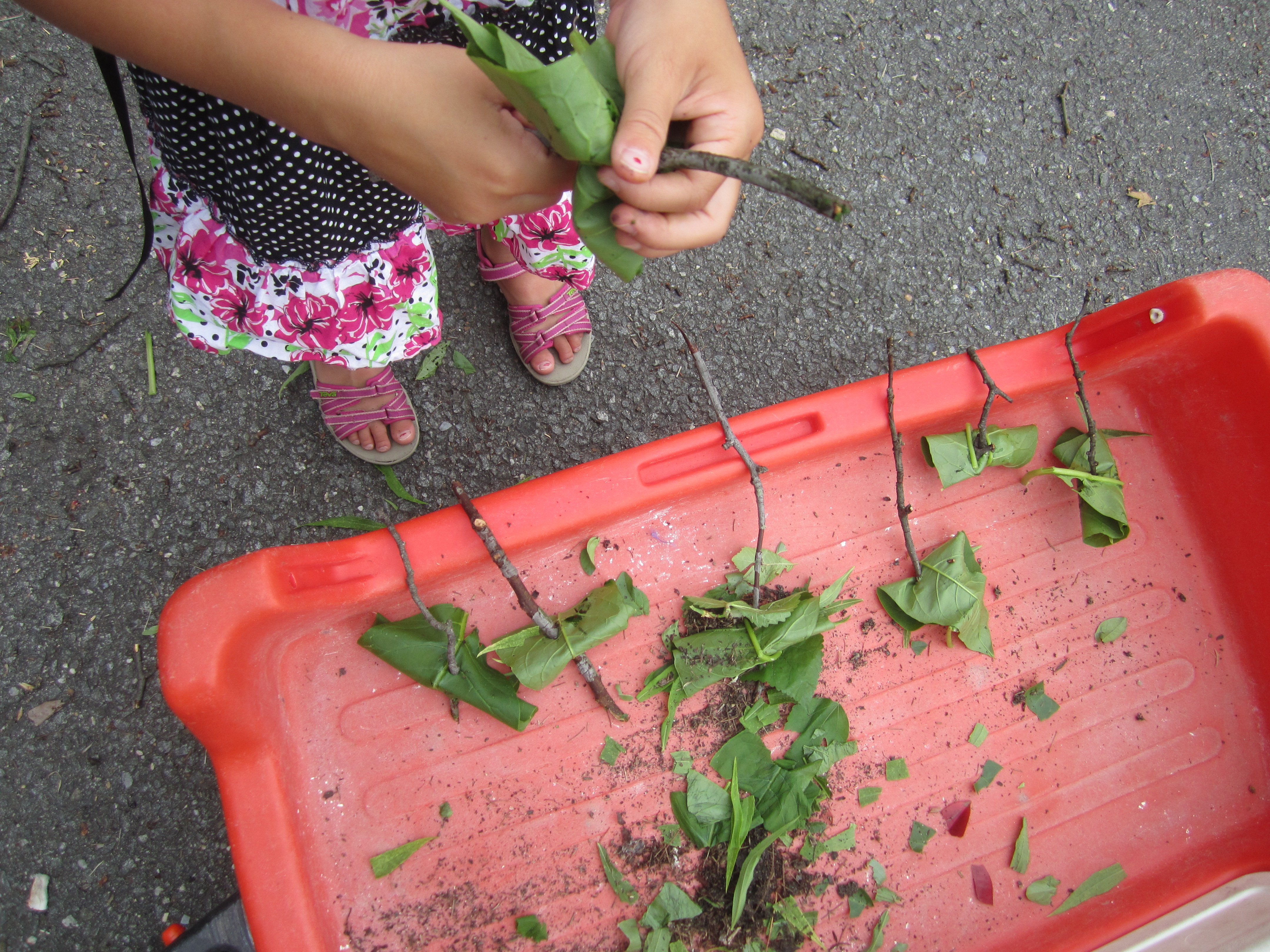 Children arrange play "food" made of leaves.