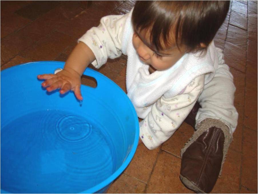 Baby splashing water in a bowl.