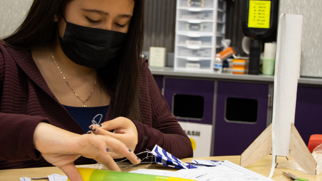How does a parachute’s design affect the speed of descent and landing location of a model rocket?