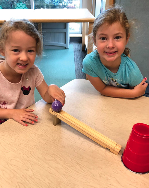 Students explore the ball and ramp setup.